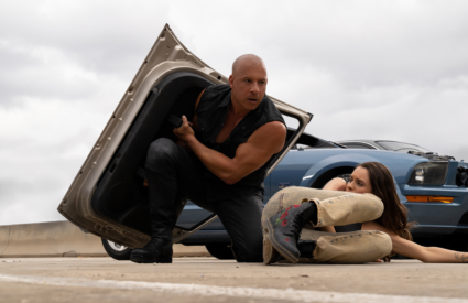 Dominic Toretto (Vin Diesel) protects female with car door.